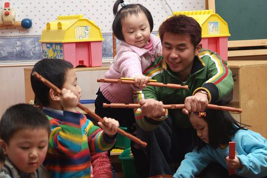 A preschool teacher plays with children in his classroom in Shanghai. (Photo provided to China Daily)