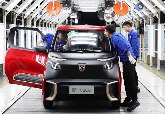 Employees check a new energy vehicle that is about to roll off the production line of a General Motors factory in Qingdao, Shandong province. [Photo provided to China Daily]