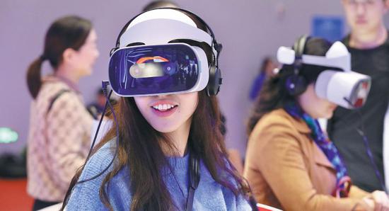 Visitors to the Light of the Internet Expo, part of the World Internet Conference, try a wearable musical device using virtual reality technology. (Photo by Zhu Xingxin/China Daily)