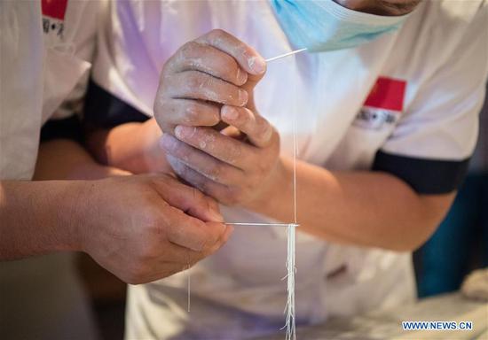 Chefs thread hand-pulled noodles through a needle during a promotion on China's Qinghai ramen in Cairo, Egypt, on June 14, 2019. Dozens of Egyptians enjoyed the taste of Chinese hand-pulled noodles during a promotion on ramen from Northwest China's Qinghai Province on Friday in the Egyptian capital Cairo. (Xinhua/Wu Huiwo)