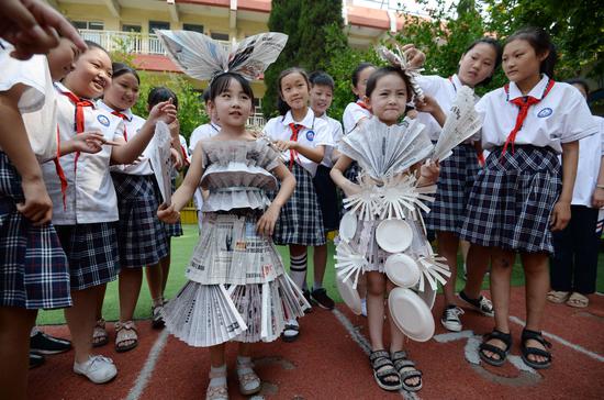 Students display costumes made from recycled newspapers and paper plates in Handan, Hebei province, on Tuesday, ahead of the National Low Carbon Day on Wednesday. (HAO QUNYING/FOR CHINA DAILY)