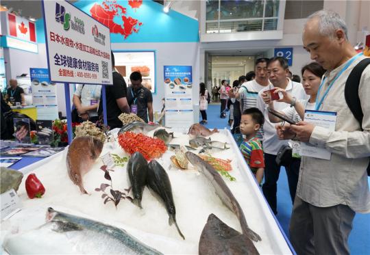 Visitors look at aquatic products at the stand of a Japanese company during a seafood expo in Fuzhou, capital of Fujian Province. (Photo/Xinhua)