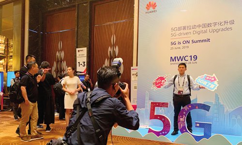 Attendees to the MWC19 Shanghai take photos in front of a 5G logo ahead of the event on Tuesday. (Photo: Chen Qingqing/GT)
