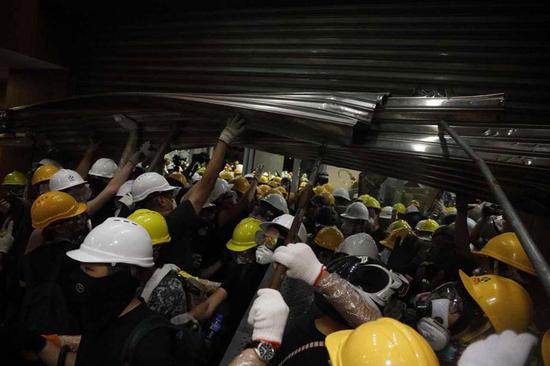 Protesters smash through glass doors and metal shutters to storm into the LegCo complex on July 1, 2019. (Photo/chinadaily.com.cn)
