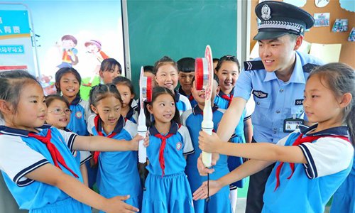 Pupils hold stop signs during a safety education event at the No.1 Primary School of Donggang Township in Qinhuangdao, North China's Hebei Province, June 27. Safety education activities are held across China to help raise students' awareness about safety for a safe summer vacation. （Photo/Xinhua）