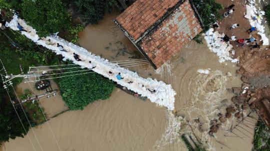 Villagers and Armed Police officers distribute sandbags to contain floodwaters in Hengnan, Hunan province, on July 10, 2019. (ZHOU WEI/FOR CHINA DAILY)