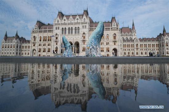 Whale sculptures swimming in plastic trash displayed in Budapest