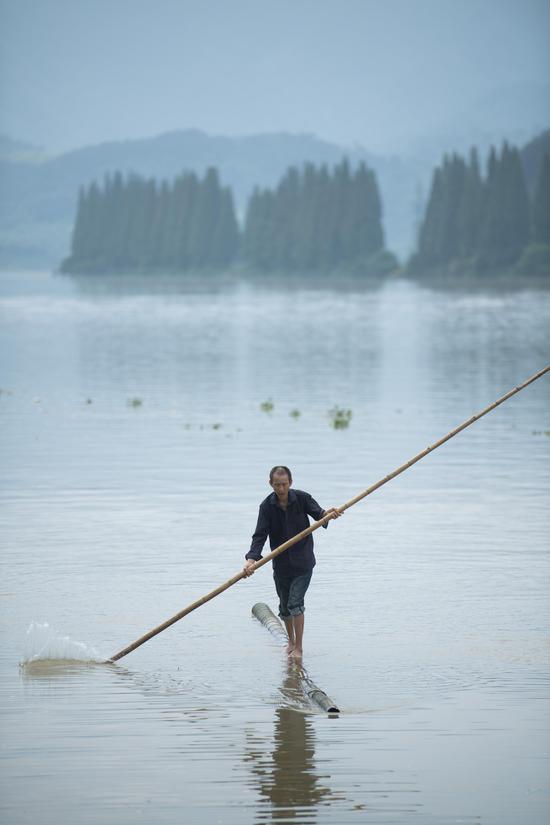 Fang Shuyun, 54, a native of Jiande City, crosses Xin'an River using two bamboo poles in Jiande City, east China's Zhejiang Province, July 11, 2019. Fang learned the trick when he was a kid. (Xinhua)