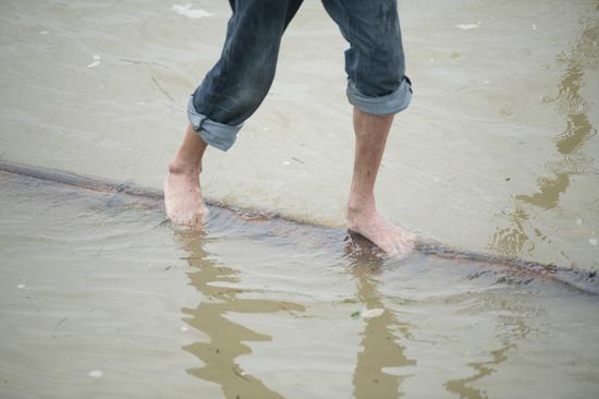 Fang Shuyun, 54, a native of Jiande City, crosses Xin'an River standing on a bamboo pole in Jiande City, east China's Zhejiang Province, July 11, 2019. Fang learned the trick when he was a kid. (Xinhua)