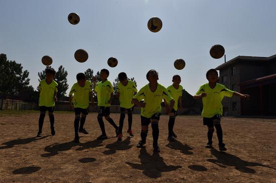 Students of Sima Primary School practise football in Xiaoyi City, north China's Shanxi Province, May 17, 2016. Many village schools have set up more sports courses during these years as they are encouraged to add more physical education classes if conditions permit. (Xinhua/Zhan Yan)