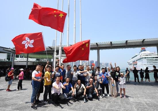 People wave the Chinese national flag and the flag of the Hong Kong Special Administrative Region(HKSAR) at a pier in Tsim Sha Tsui of Hong Kong, south China, Aug. 8, 2019. (Xinhua/Lui Siu Wai)