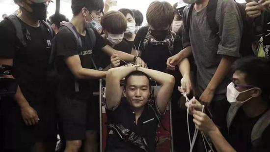 Fu Guohao, a reporter with Global Times, is bound with zip ties by violent protesters. （Global Times Photo）