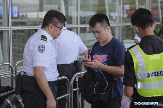 An airport security officer checks information of a passenger at Hong Kong International Airport in Hong Kong, south China, Aug. 14, 2019.  (Xinhua/Wang Shen)