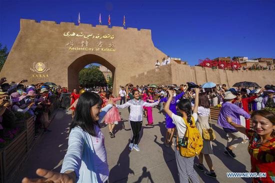 Tourists dance with staff members in the ancient city of Kashgar, northwest China's Xinjiang Uygur Autonomous Region, July 8, 2019. In the first half of 2019, the ancient city of Kashgar received over 310,000 tourists. (Xinhua/Zhao Ge)