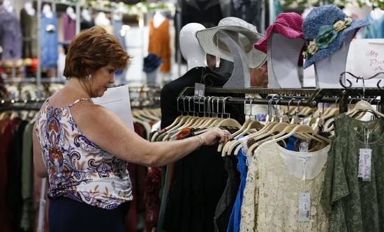 A woman browses clothes during the Offprice Show in Las Vegas, the United States, Aug. 11, 2019. (Xinhua/Li Ying)