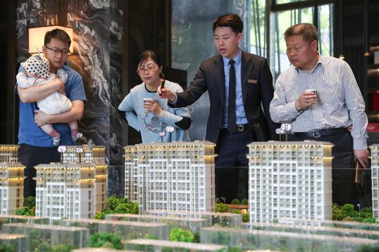 Potential homebuyers examine property models at a sales site in Shanghai. [Photo provided to China Daily]