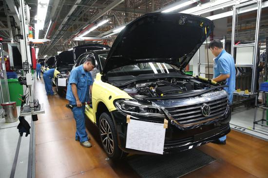 Employees put finishing touches to cars at the SAIC Volkswagen factory in Shanghai. [Photo/Xinhua]