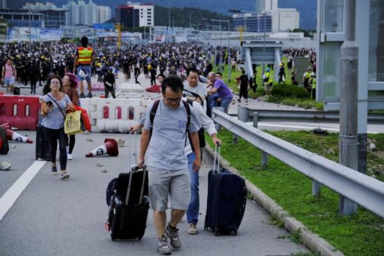 Passengers walk to the Hong Kong International Airport blocked by radical protesters and have to drag their luggages along the way to the terminal of the airport in South China's Hong Kong on Sept. 1, 2019. (Xinhua)