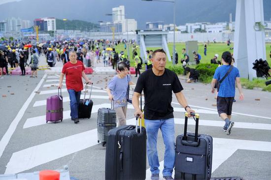 Passengers stride over barriers and walk to airport as radical protesters block the roads outside the Hong Kong International Airport in south China's Hong Kong, Sept. 1, 2019. (Xinhua)