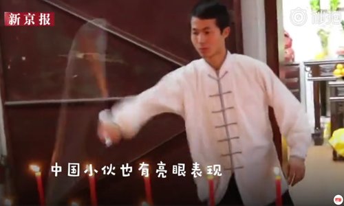 A Chinese martial arts master sets a world record for extinguishing most lit candles in one minute using a two section nunchaku. (Photo/Screenshot from the Beijing News)
