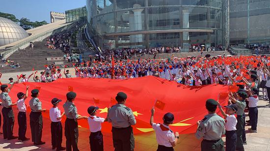 Teenagers from the Hong Kong Special Administrative Region and Shenzhen display the national flag during an event to celebrate the 70th anniversary of the founding of the People's Republic of China at Shenzhen Children's Palace, Shenzhen, China, Sept 21, 2019. (Photo/China Daily)
