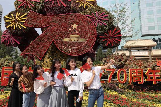 People take selfies in front of a flowerbed themed 