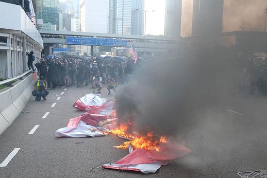 A group of black-clad protestors tore down and burned a banner reading 