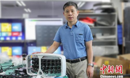 Zeng Xiaoyang pose for a picture with the artificial intelligence (AI)-enabling 500 megapixel cloud camera device. (Photo/China News Service)