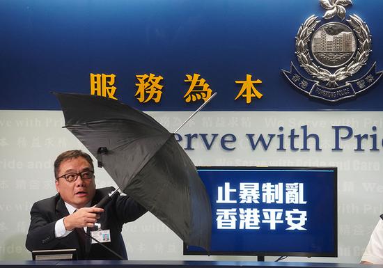 During a news conference held by police in Hong Kong on Monday, Li Kwai-wah, senior superintendent of the Organized Crime and Triad Bureau, displays a special umbrella that had been used by radical protesters. (Photo/China Daily)