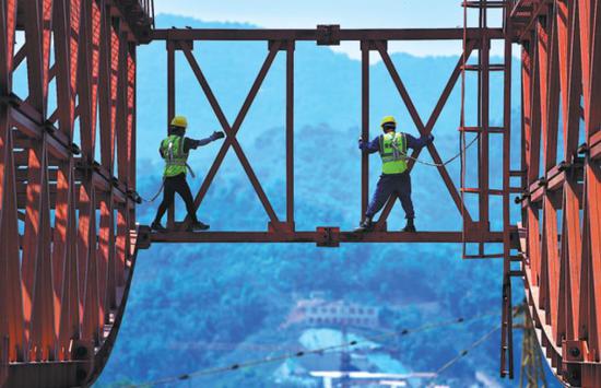 Workers walk along a steel girder at a construction site of the China-Laos Railway, a Belt and Road project, in Pu’er, Yunnan province, in April. (Photo/Xinhua)