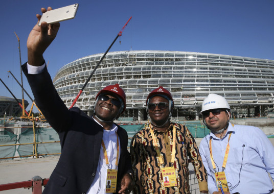 Foreign journalists gather on Tuesday in front of the National Speed Skating Oval, which is under construction and will be used during the 2022 Beijing Winter Olympics.  (Photo by Chen Zebing/China Daily)