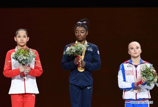 Gold medalist Simone Biles of the United States (C), silver medalist Tang Xijing of China (L) and bronze medalist Angelina Melnikova of Russia stand on the podium during the awarding ceremony of the Women's All-Around Final of the 2019 FIG Artistic Gymnastics World Championships in Stuttgart, Germany, Oct. 10, 2019. (Xinhua/Lu Yang)