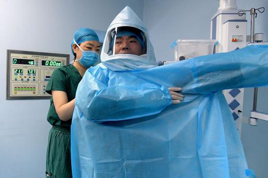 A doctor puts on a disposable operating coat before surgery before he starts to perform a surgery for an AIDS patient at Henan Infectious Disease Hospital in Zhengzhou, capital of central China's Henan Province, July 31, 2019. (Xinhua/Li An)