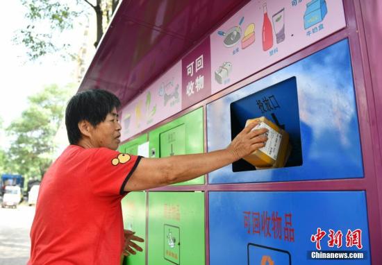 A resident puts garbage into a trash can in Beijing. (File photo/China News Service)