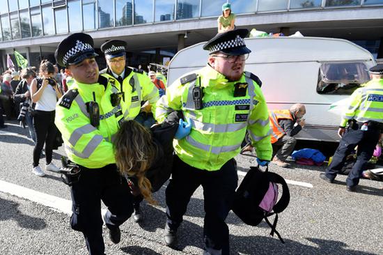 Police officers carry away an activist as Extinction Rebellion protesters block a road with caravan in central London, Britain, October 15, 2019.  (Photo/Agencies)