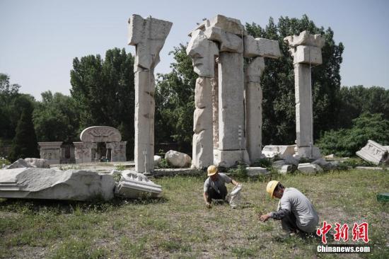 Staff members clean up weeds at ruins of Yuanying Guan (Immense Ocean Observatory) at Yuanmingyuan in Beijing, capital of China, May 23, 2018.  （Photo/China News Service）