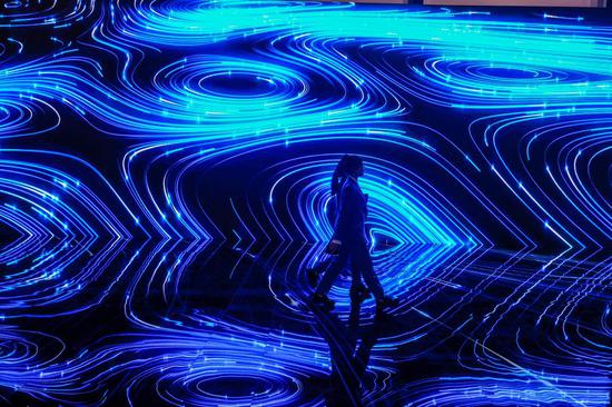 Staff members walk by a giant screen in Wuzhen International Internet Exhibition and Convention Center in Wuzhen, east China's Zhejiang Province, Oct. 19, 2019. The 6th World Internet Conference is scheduled to take place here from Oct. 20 to 22. (Xinhua/Xu Yu)