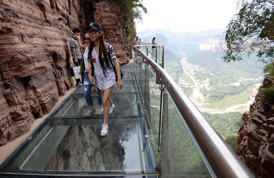 Tourists experience a glass walkway in a scenic area in Handan, Hebei Province, in September. (Photo / China Daily)