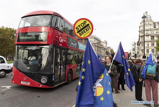 A bus passes by anti-Brexit protesters outside the Houses of Parliament in London, Britain, on Oct. 28, 2019. The British House of Commons on Monday voted against a government motion calling for an early general election on Dec. 12. (Xinhua/Han Yan)