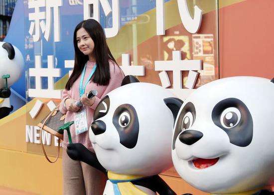 A visitor poses for photos with Jinbao, mascot of the China International Import Expo (CIIE), during the second CIIE in Shanghai, east China, Nov. 8, 2019. (Xinhua/Liu Ying)