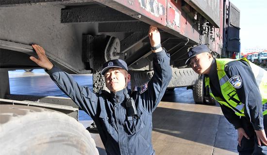 Naranmand (left) checks underneath a truck at the China-Mongolia border at Bayannuur, Inner Mongolia autonomous region, last month. (Photo/China Daily)
