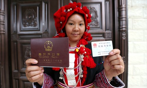 A woman dressed in the traditional costume of the Yao ethnicity holds her Chinese ID card and household registration. (Photo: Cui Meng/GT)