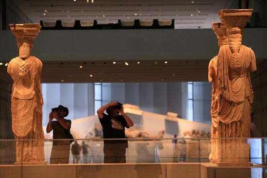 Visitors take photos of Caryatids on display at the Acropolis Museum in Athens, Greece, Nov. 7, 2019. (Xinhua/Marios Lolos)