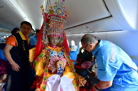 The cabin crew adjust the seat for the statue of Mazu on the airplane departing from Xiamen, Nov. 14, 2019. (Xinhua/Wei Peiquan)