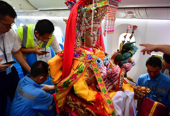 The cabin crew adjust the seat for the statue of Mazu on the airplane departing from Xiamen, Nov. 14, 2019. (Xinhua/Wei Peiquan)