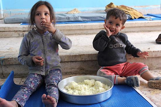 Displaced children have a meal at a school that has been turned into a shelter in Hasakah Province, Syria, on Oct. 21, 2019.(Str/Xinhua)