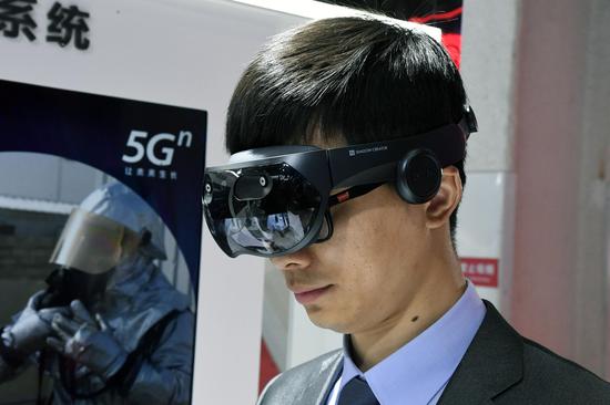 A staff member displays a Mixed Reality (MR) terminal device at the 2019 World 5G Convention in Beijing, capital of China, Nov. 21, 2019. (Xinhua/Ren Chao)