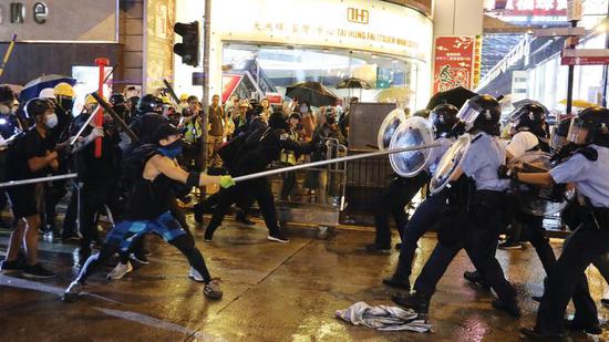 Radical protesters attack police officers with metal rods at an unauthorized assembly in Hong Kong. （Photo/China Daily）