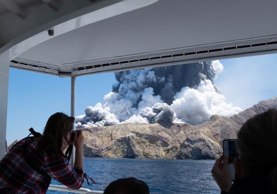 A person takes photos of volcanic eruption at New Zealand's White Island, Dec. 9, 2019. (Photo provided by Michael Schade/Handout via Xinhua)