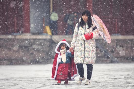 A woman and girl enjoy wintry scenery at Beijing's Working People's Cultural Palace as snow falls in the capital on Monday. (LIU CHANG/FOR CHINA DAILY)